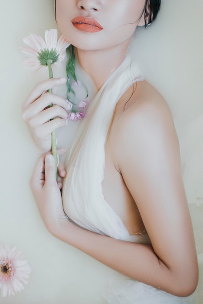 Sezione centrale di una donna che tiene un fiore sullo sfondo bianco