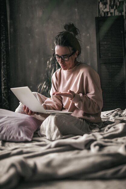 Sezione centrale di una donna che usa il telefono cellulare mentre è seduta a letto a casa