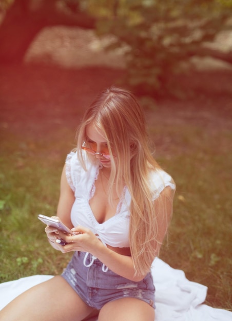 Sezione centrale di una donna che usa il telefono cellulare mentre è seduta all'aperto.