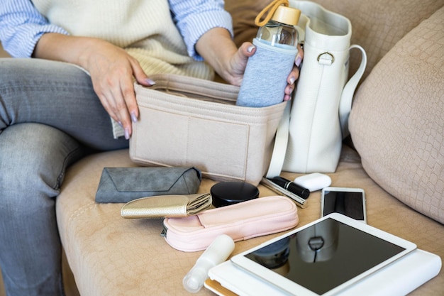 Sezione centrale di una donna che usa il telefono cellulare mentre è seduta sul divano a casa