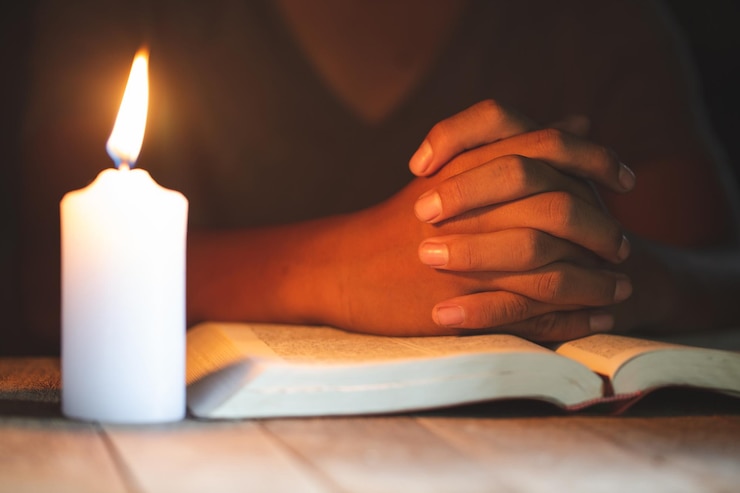 Foto sezione centrale di una donna con una candela sul tavolo che legge un libro