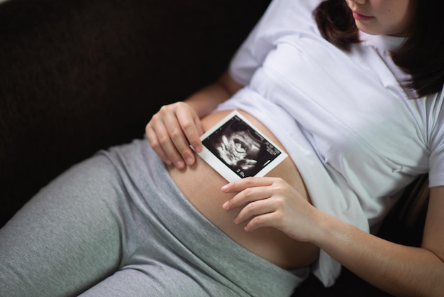 Sezione centrale di una donna incinta che tiene in mano una radiografia a casa