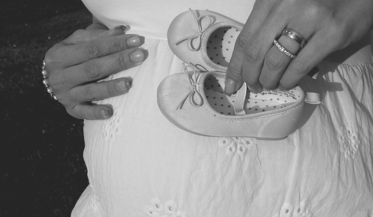 Foto sezione centrale di una donna incinta che tiene le scarpe
