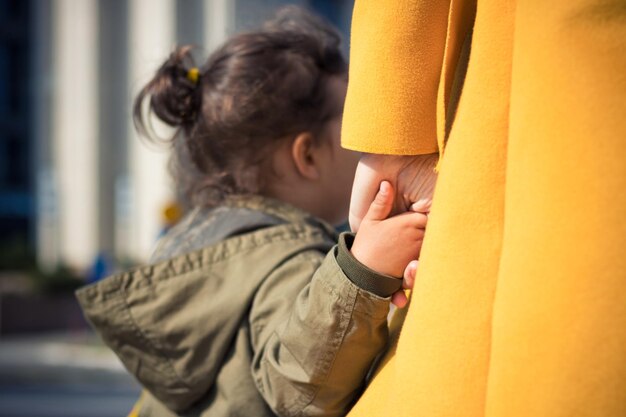 Sezione centrale di una madre che tiene la mano di sua figlia sulla strada in città