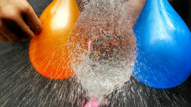 Foto sezione centrale di una persona che fa scoppiare i palloncini d'acqua
