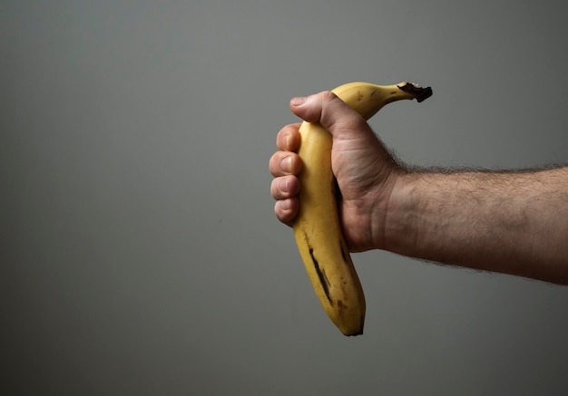 Sezione centrale di una persona che tiene una banana sullo sfondo bianco