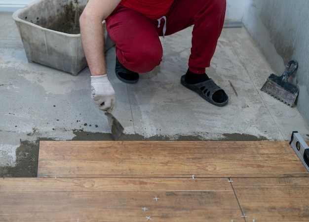 Sezione inferiore dell'uomo che lavora usando cemento sul pavimento di legno