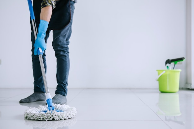 Sezione inferiore dell'uomo che pulisce il pavimento in piastrelle a casa