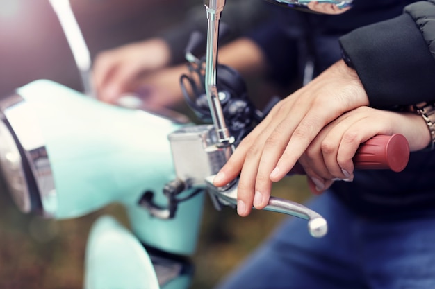 Sezione mediana di una giovane coppia che sorride mentre guida uno scooter in città in autunno