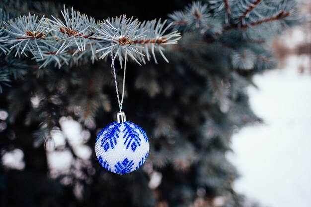 Sfera blu e bianca di natale sul ramo di albero di abete