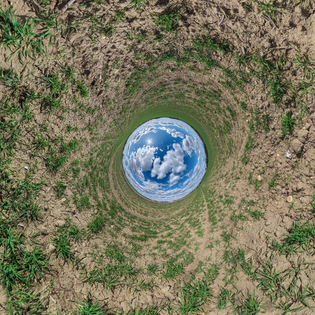 Sfera del cielo blu nel mezzo del vorticoso campo verde Inversione del minuscolo pianeta Trasformazione del panorama sferico Curvatura di 360 gradi dello spazio