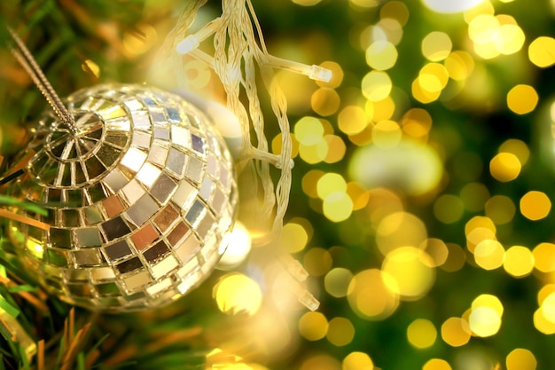 Sfera di cristallo decorata sull'albero di pino il giorno di Natale con il bokeh dell'illuminazione di Natale