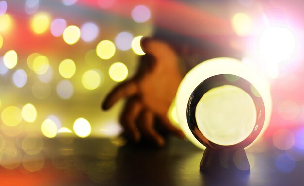 Sfera di cristallo sul tavolo con luci bokeh dietro Sfera di vetro con concetto di previsione della luce bokeh colorato