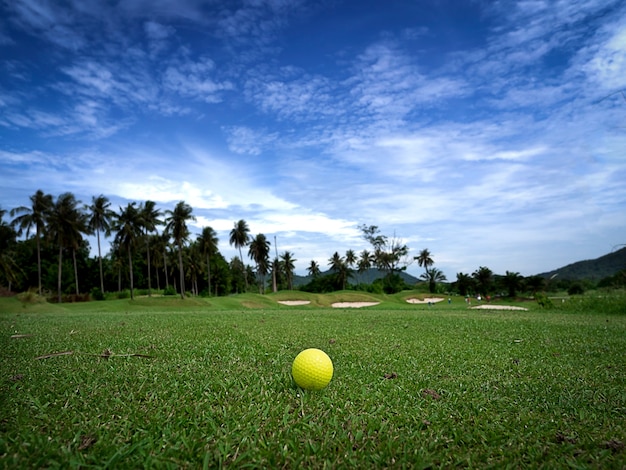 Sfera di golf gialla sul bello T con fondo del cielo di mattina