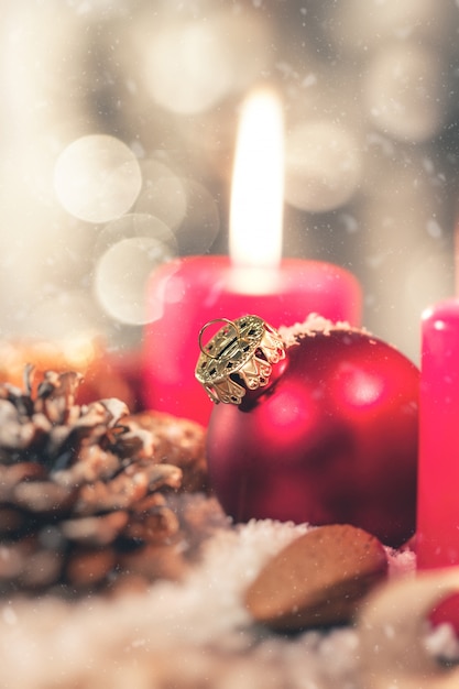 Sfera di natale con la decorazione con le candele, i coni di abete, i dadi, la neve ed il nastro, primo piano, tonificato