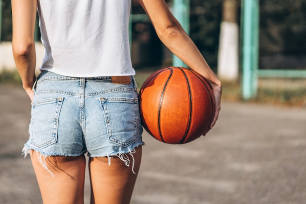 Sfera di pallacanestro della holding della ragazza graziosa, retrovisione.