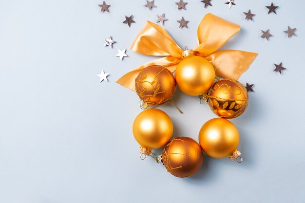 Sfera dorata e gialla di natale con il nastro su priorità bassa blu con le stelle d'argento