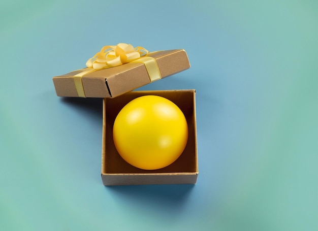 Sfera gialla in scatola regalo o concetti a sorpresa su sfondo divertente