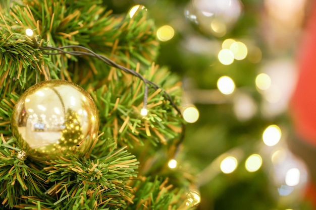 Sfere dorate di natale decorate sull'albero di pino il giorno di Natale con fondo confuso