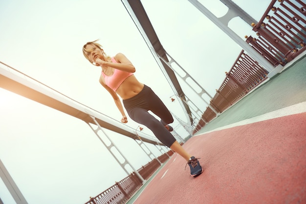 Sfidando me stesso per tutta la lunghezza di una giovane e forte donna bionda in abbigliamento sportivo che fa jogging