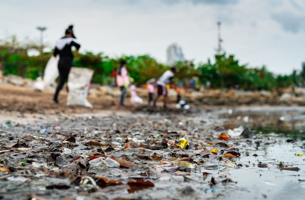 Sfocato di volontari che raccolgono rifiuti. Inquinamento ambientale della spiaggia