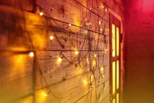 Sfocatura luci di Natale su assi di legno e porta. Ghirlanda luminosa brillante. Sfondo di luci di Capodanno