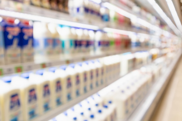 sfocatura scaffali del frigorifero del supermercato con bottiglie di latte fresco e prodotti lattiero-caseari