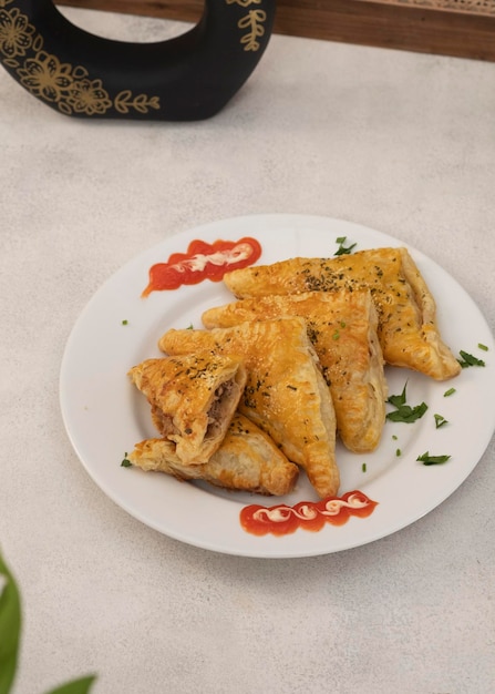 Sfogliatina di tonno su un piatto bianco con salsa al peperoncino. Una deliziosa pasticceria salata per la colazione quotidiana