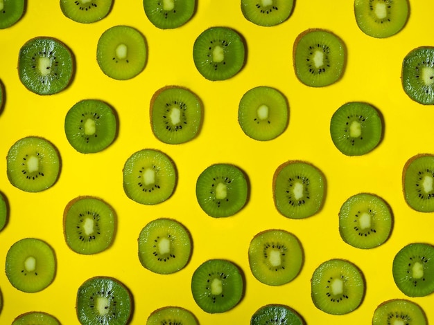 Sfondio di molte fette di kiwi Kiwi tagliato su uno sfondo giallo Concetto di cibo crudo Frutta tagliata Modello di frutta verde matura
