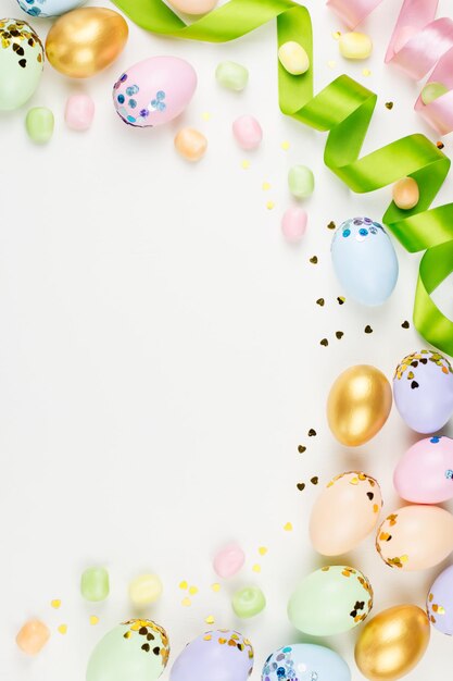 Sfondio festivo di Pasqua con uova decorate fiori caramelle e nastri in colori pastello su bianco Copia spazio