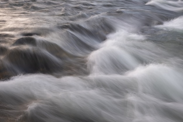 Sfondo astratto da una lunga esposizione del flusso d'acqua in un primo piano del fiume di montagna