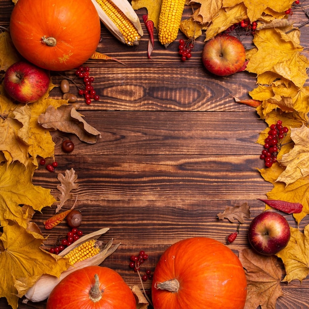 Sfondo autunnale con foglie di acero gialle, zucche, mele rosse e bacche.