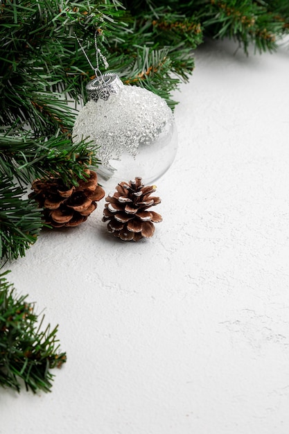 Sfondo bianco di Capodanno o Natale decorato con giocattoli, pigne e rami di abete