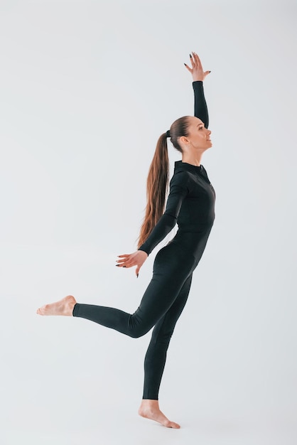Sfondo bianco Giovane donna in abiti sportivi facendo ginnastica al chiuso