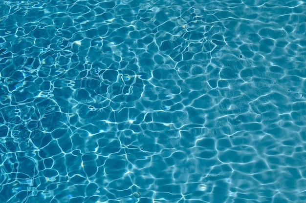 Sfondo blu acqua in piscina con riflessi dal sole. Orientamento orizzontale