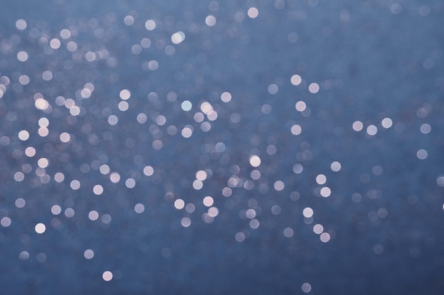 Sfondo blu festivo di luci glitter argento. Astrazione sfocata invernale