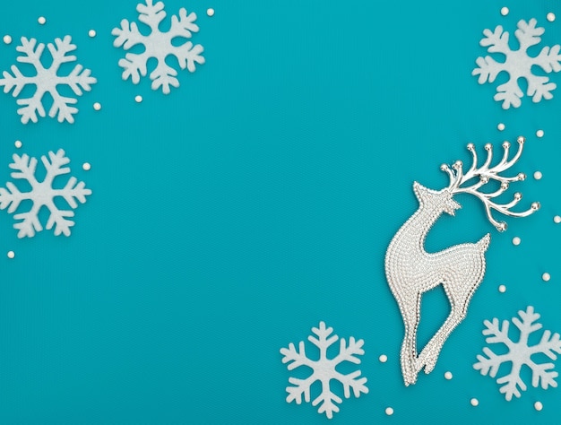 Sfondo blu Natale o inverno con un cervo e fiocchi di neve bianchi e perline. Stile piatto laici con spazio di copia.