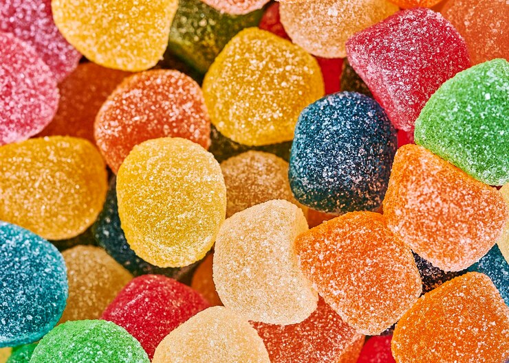 Sfondo colorato di caramelle gommose ricoperte di zucchero gialle, arancioni e rosse