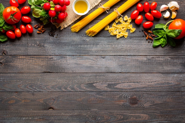 Sfondo cornice di pasta, diversi tipi di pasta secca con verdure ed erbe, vista dall'alto