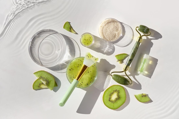 Sfondo cosmetico per la cura della pelle. Erboristeria con fette di kiwi e foglie di palma. Scrub allo zucchero fatto in casa. Luce solare naturale, ombre lunghe. Increspature dell'acqua. Sfondo naturale per la cura della pelle. Composizione quadrata.