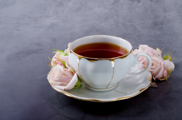 Sfondo da tè con tazza da tè in porcellana bianca vintage, delicate rose rosa