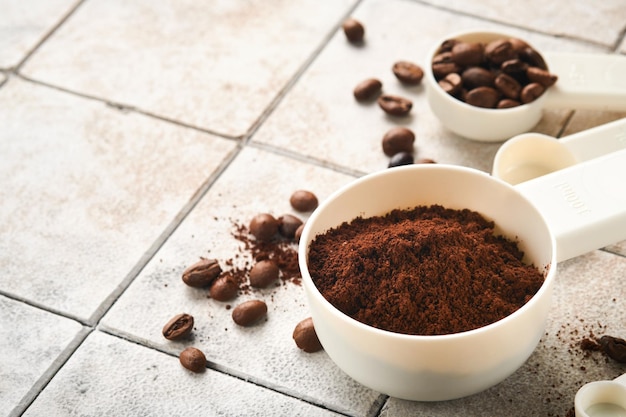 Sfondo del caffè Misurini con caffè macinato e fagioli su una vecchia piastrella incrinata sullo sfondo del tavolo Ingredienti per fare il caffè Vista dall'alto con spazio per il testo