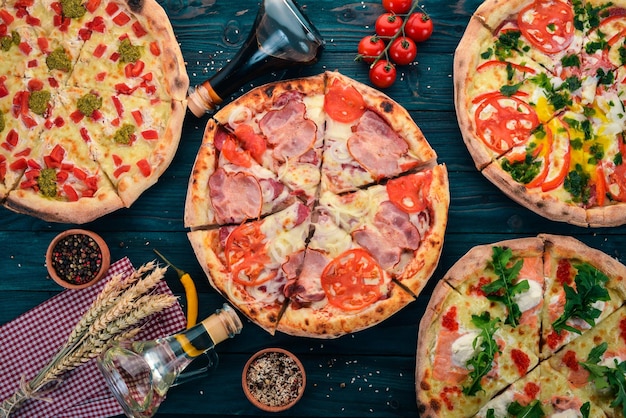 Sfondo del cibo italiano. Assortimento di pizza. Su uno sfondo di legno nero. Spazio libero per il testo. Vista dall'alto.