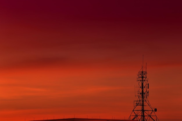 Sfondo del cielo rosso e arancione con silhouette della torre del telefono