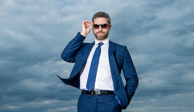 Sfondo del cielo uomo professionale Uomo brizzolato regolazione occhiali da sole Uomo felice in tuta all'aperto