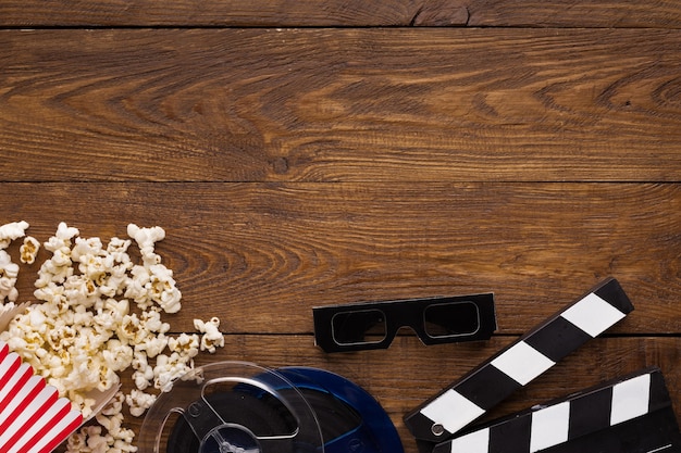 Sfondo del cinema, vista dall'alto. Ciak, popcorn, soda e occhiali 3D sul tavolo di legno, copia spazio. Accessori per i frequentatori di film, concetto di cinematografia