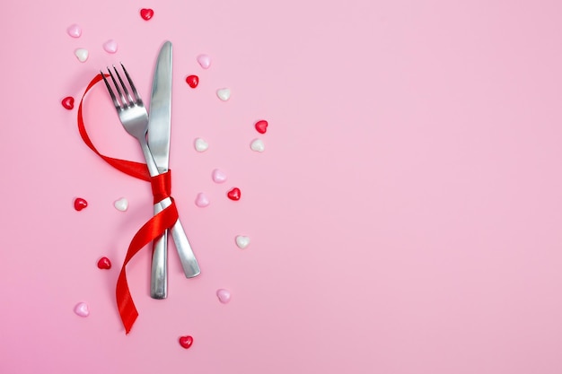 Sfondo del pasto di San Valentino con cuori di nastro rosso forchetta coltello piatto bianco e tovagliolo per le vacanze romantiche Splendido sfondo con ristorante vuoto Concetto Piatto lay Alta qualità