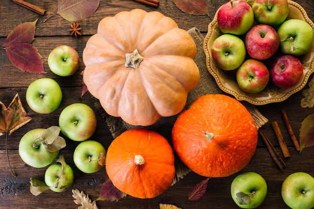 Sfondo del ringraziamento, zucche, mele e spezie su un tavolo di legno