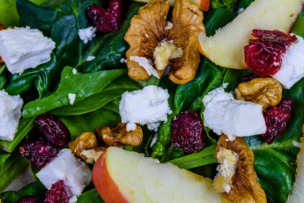 Sfondo dell'insalata con foglie di spinaci formaggio feta mirtilli rossi noci e mela