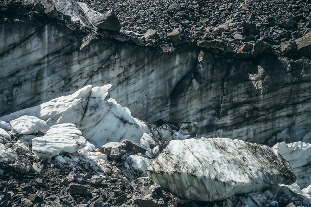 Sfondo della natura con cascata di ghiaccio vicino alla parete del ghiacciaio con crepe e graffi. Fondale naturale con parete ghiacciata e blocchi di ghiaccio. Bellissimo paesaggio con pareti glaciali lucide e blocchi di ghiaccio alla luce del sole.